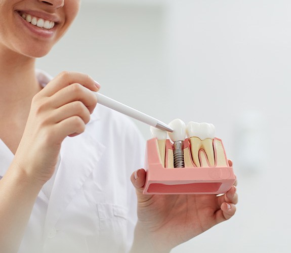 Dentist pointing to sample implant with white pen