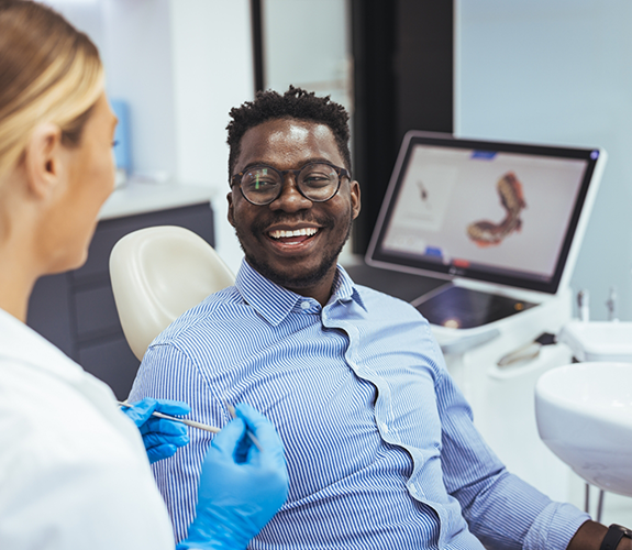 Man in dental chair grinning at his dentist