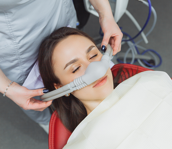 Woman in dental chair relaxing with nitrous oxide mask over her nose