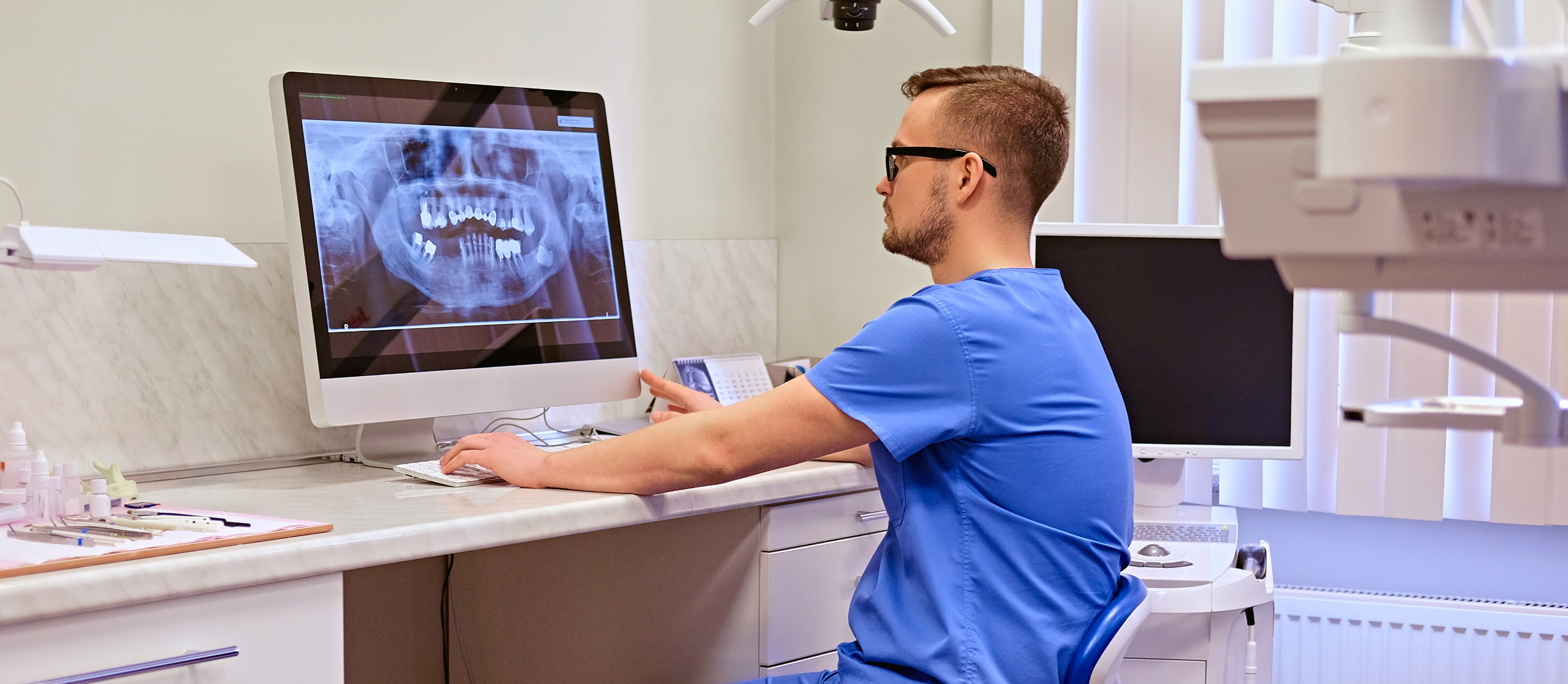 Dentist looking at a computer screen showing an x ray of a patients teeth