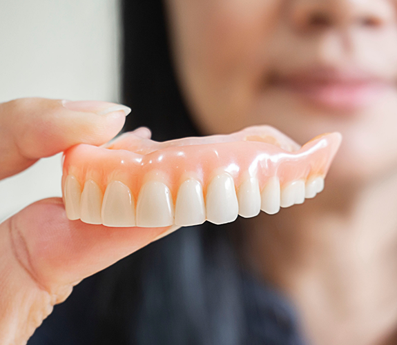 Woman holding a full denture