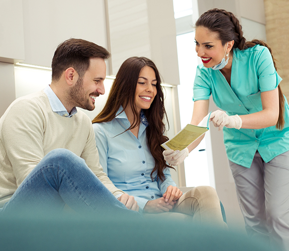 Dental team member showing a pamphlet to two patients