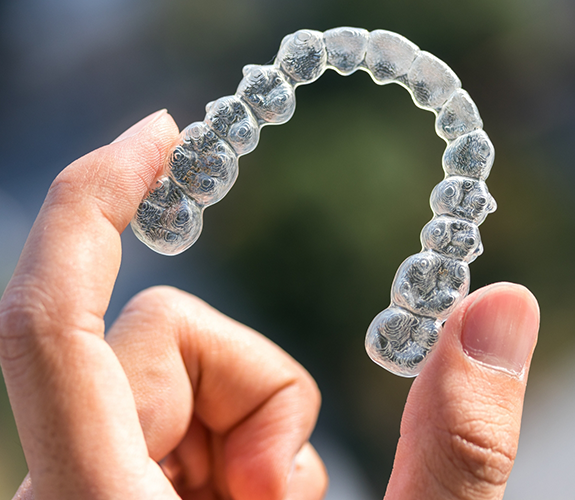 Hand holding an Invisalign clear aligner