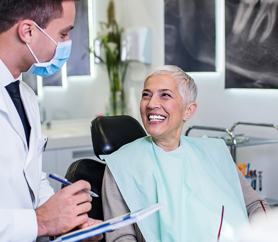 Senior woman in dental chair grinning at her dentist