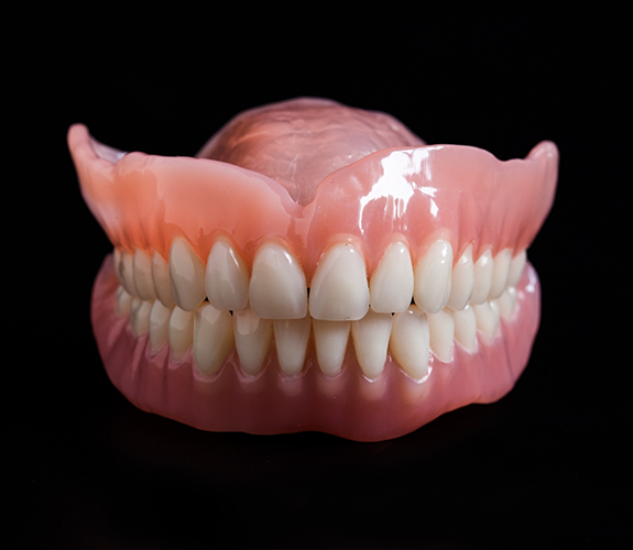 Set of full dentures against black background