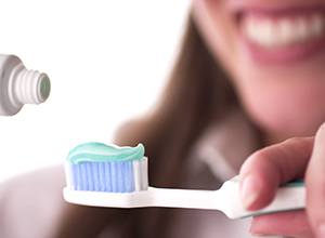 Lady applies toothpaste to brush