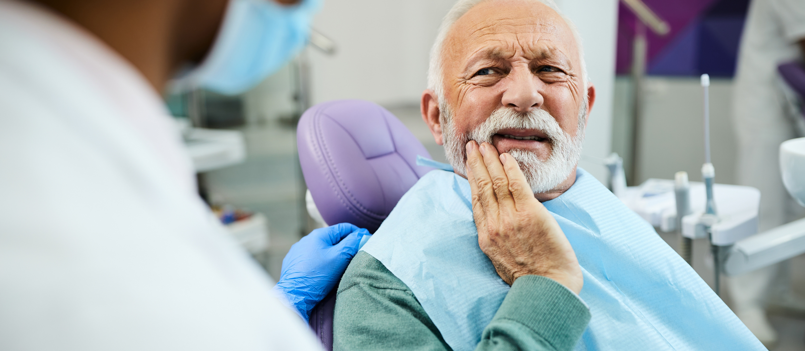 Senior dental patient holding his cheek in pain before root canal treatment