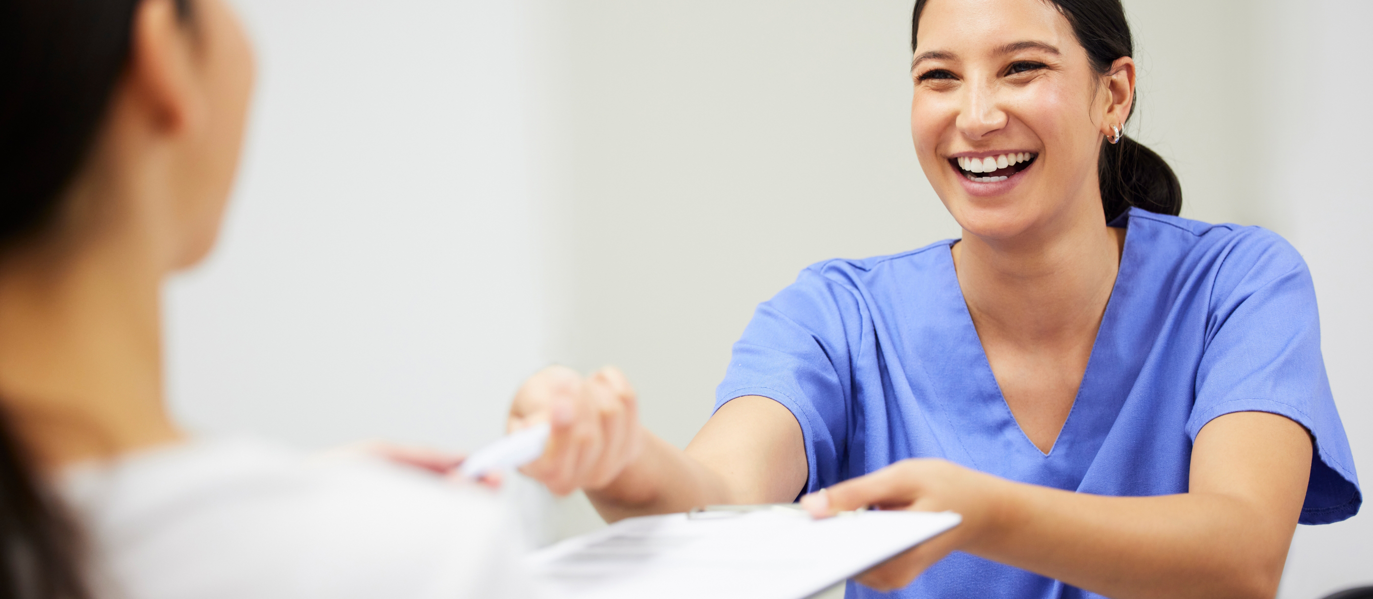 Dental team member smiling and handing paperwork to a patient