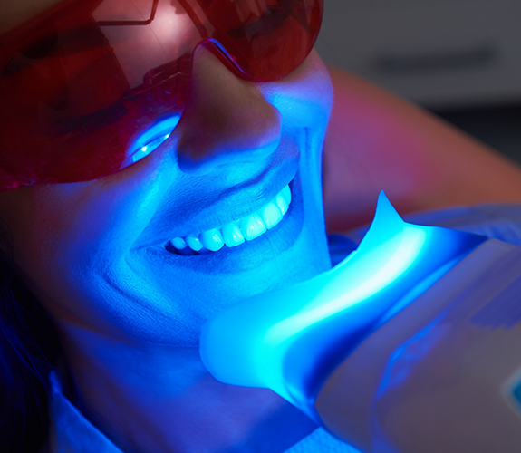 Woman in dental chair getting her teeth professionally whitened