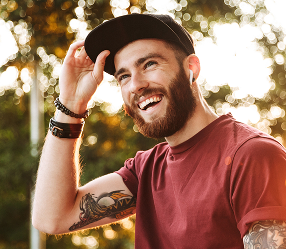 Young man with tattoo sleeves smiling outdoors