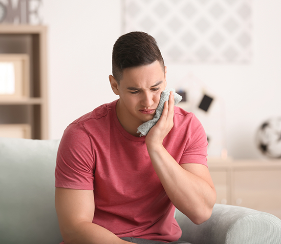 Man holding a cold compress to his cheek